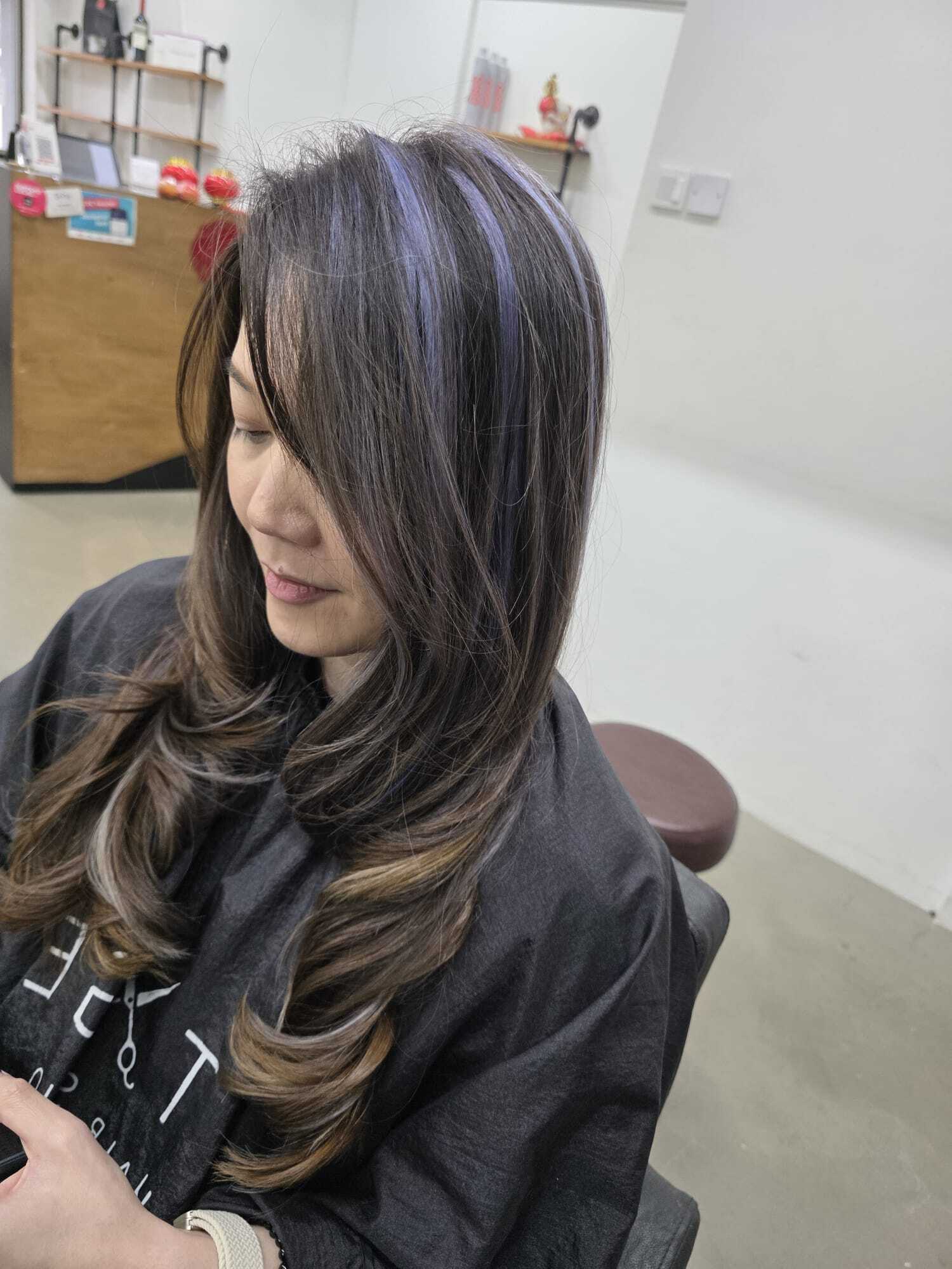Brown hair with violet peekaboo highlights and curled ends styled at Stage Hair Studio